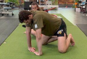 Rene on his hands and knees with both hands turned in facing each other.  He is stretching them as a bjj armbar mobility exercise